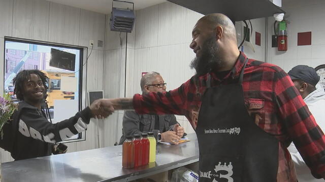 Chef Milly Medley shakes hands across the counter with a customer at Table for 3 