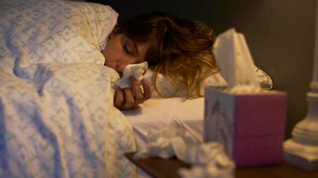 Sick woman using tissues in the bed 