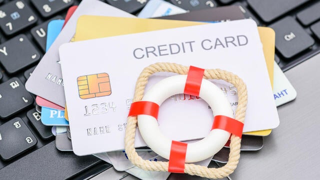 Household and credit card debt, personal loan, payment overdue, financial problems : Red lifebuoy or lifebelt atop a stack of credit cards on a laptop, depicting problems in repaying credit card debt. 